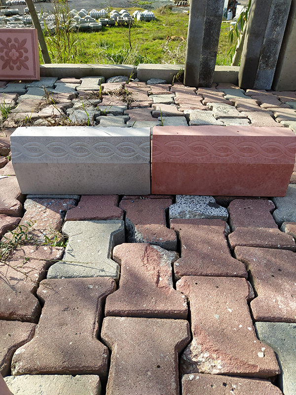 Gri ve kırmızı renkte, örgülü desenli, 40 cm uzunluğunda dekoratif bordür taşları kilitli parke zemin üzerinde.