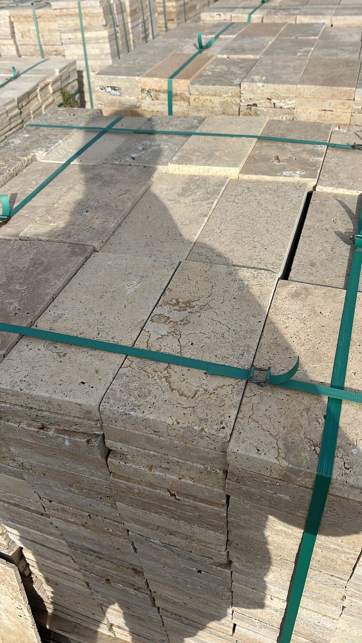 Paletler halinde paketlenmiş 15x30x3 bej tonlu traverten zemin döşeme taşları, split yüzeyli doğal taş.