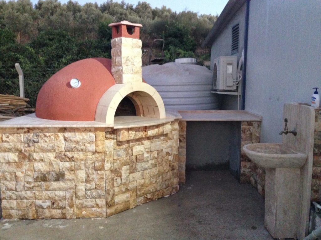 Bahçeye yapılan doğal taş kaplamalı kubbeli taş fırın ve yanındaki mermer tezgahlı lavabo ünitesi.