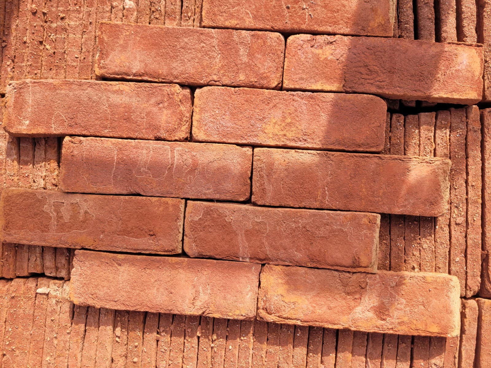 Duvar kaplaması için üst üste dizilmiş el yapımı kırmızı dekoratif tuğlalar.