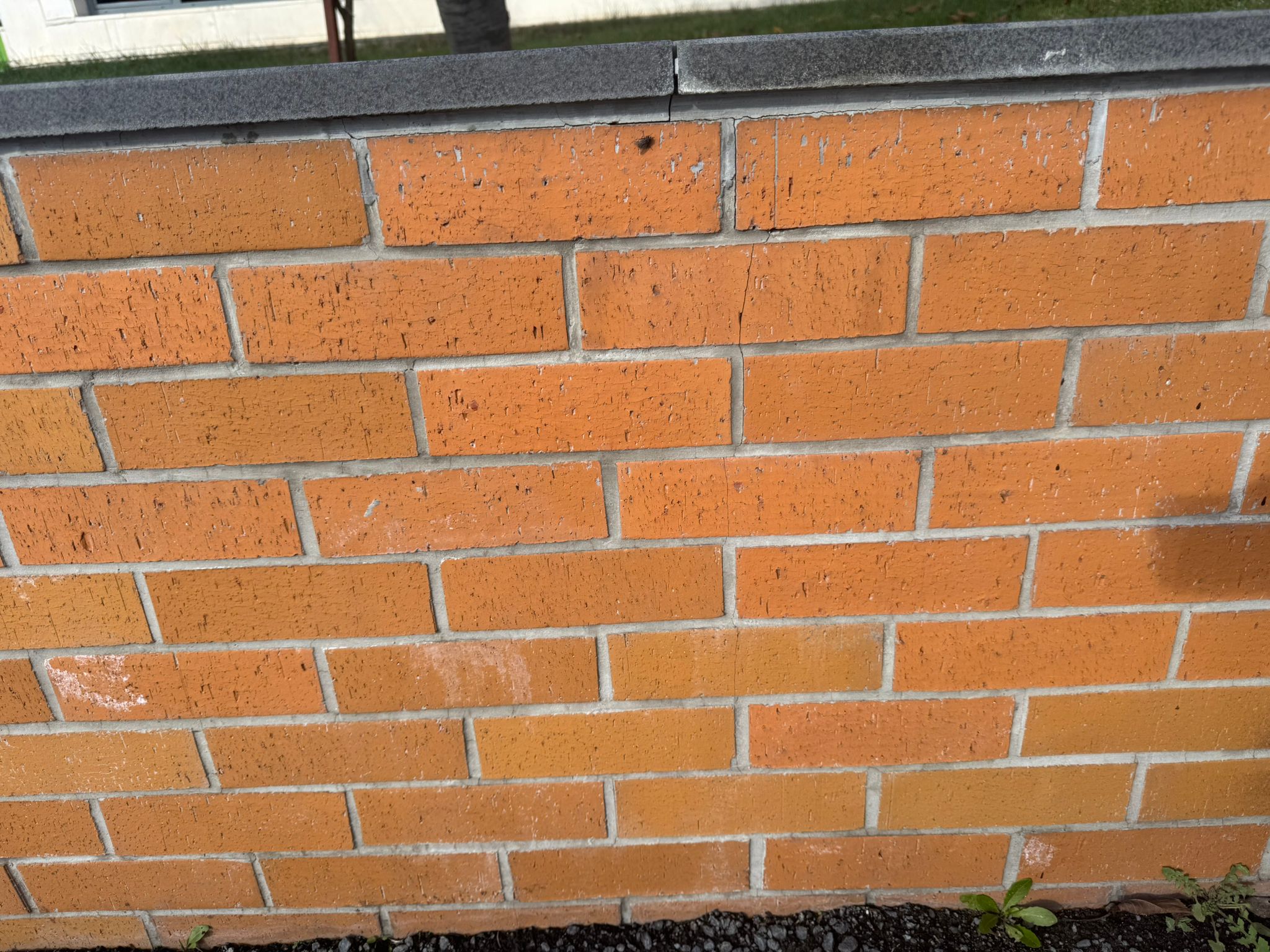 Modern bir binanın dış cephesinde uygulanmış turuncu bisküvi kaplama tuğlaları ve gri derz dolgusu.